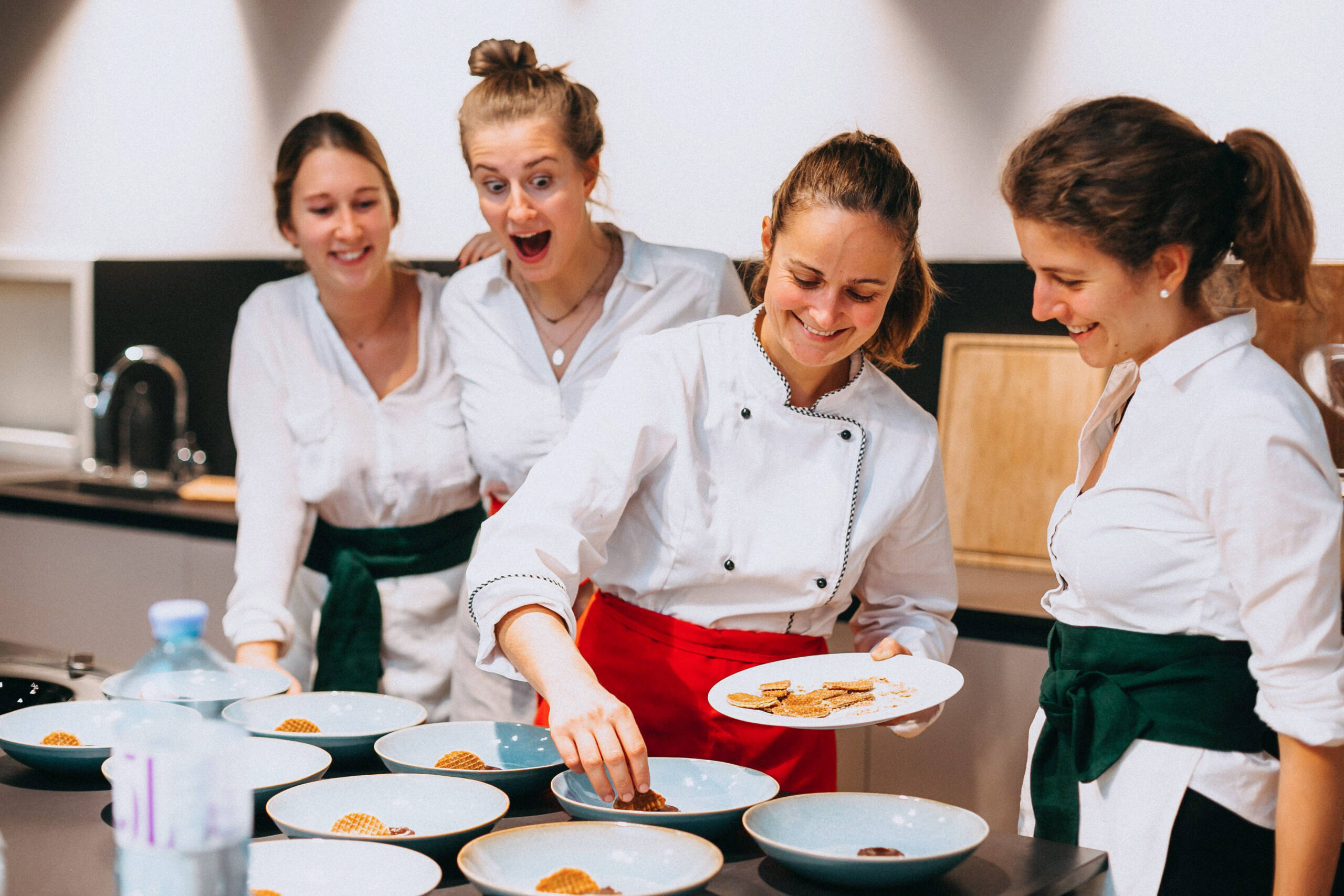 Lachendes Küchen-Team beim Anrichten der Desserts